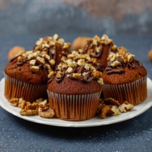 Chocolate-walnut muffins with coffee cup with walnuts on dark ba